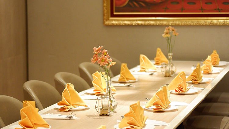 A beautifully set table with plates, napkins, and flowers, perfect for private meetings at Ganesha Ek Sanskriti Indian Restaurant