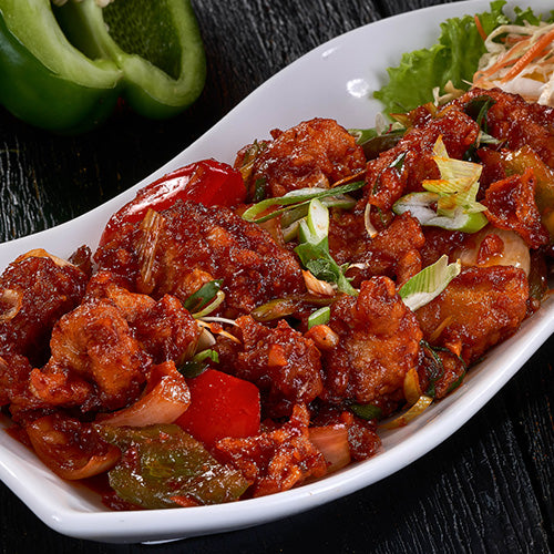 A colorful dish of Chilli Chicken with bell peppers, onions, and a spicy sauce at an Indian Restaurant