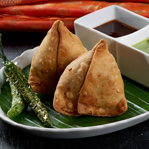A plate of crispy Samosas, a traditional Indian savory pastry filled with potatoes and green peas