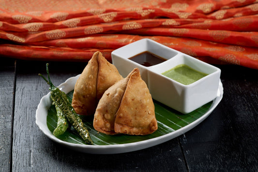 A plate of crispy Samosas, a traditional Indian savory pastry filled with potatoes and green peas