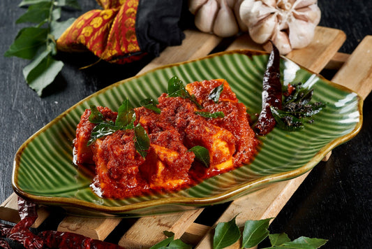 A plate of fiery red Paneer Ghee Roast, a Mangalorean delicacy known for its tangy and spicy flavor